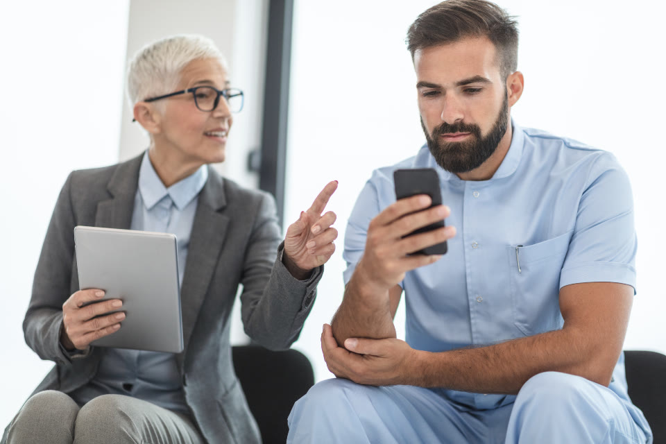 Duas pessoas da equipe conferindo um registro no celular e no tablet